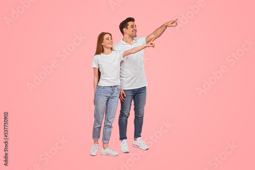 Happy young couple pointing away