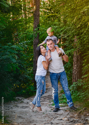 Beautiful happy Ukrainian family in the forest in summer. Mom, dad and son 2 years old in the forest.