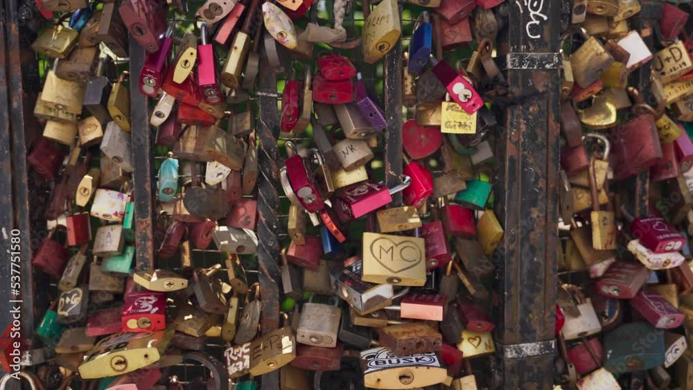 Padlocks and locks symbol of bond and love relationships hanging on metal fence. Hundreds of locks placed on metal bars with initials of lovers and couples. New rusty and old with various colors Padlocks and locks symbol of bond and love relationships hanging on metal fence. Hundreds of locks placed on metal bars with initials of lovers and couples. New rusty and old with various colors