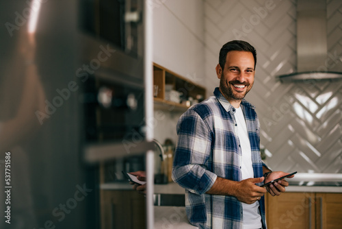 Portrait of a man holding a tablet and smiling for the camera wh