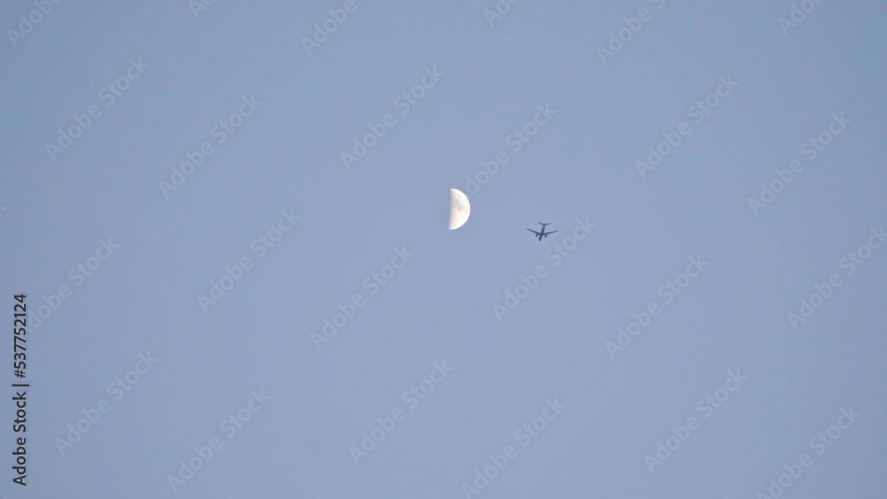The airplane flies against the background of the moon at dusk The airplane flies against the background of the moon at dusk
