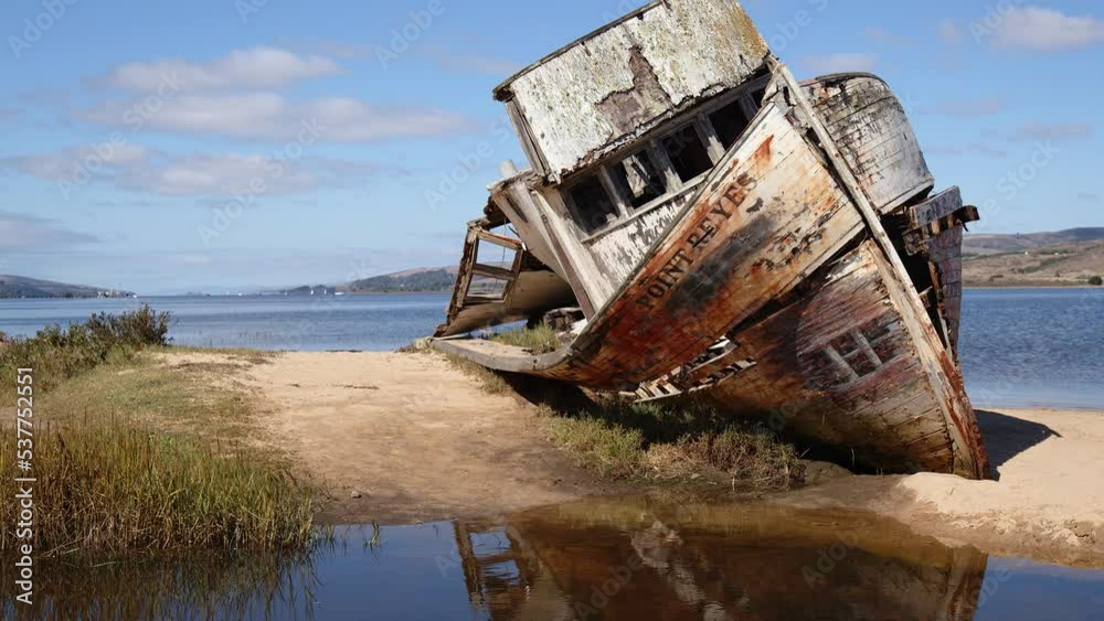 Tilting (up) shot of rotting, shipwrecked Point Reyes boat washed up on a sunny Tomales Bay shore. Tilting (up) shot of rotting, shipwrecked Point Reyes boat washed up on a sunny Tomales Bay shore.