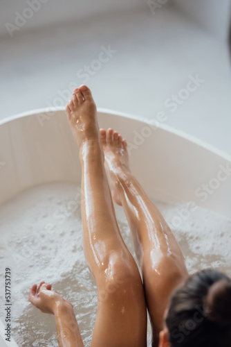 Pretty young woman taking bath at home back view
