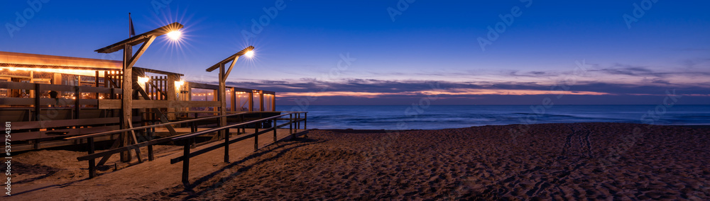 Holzbrücke bei Nacht zum Restaurant am Strand am Meer Holzbrücke bei Nacht zum Restaurant am Strand am Meer