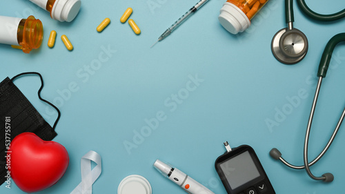 Top view glucose meter, lancet pen, insulin, stethoscope and syringe on blue background. Diabetes concept
