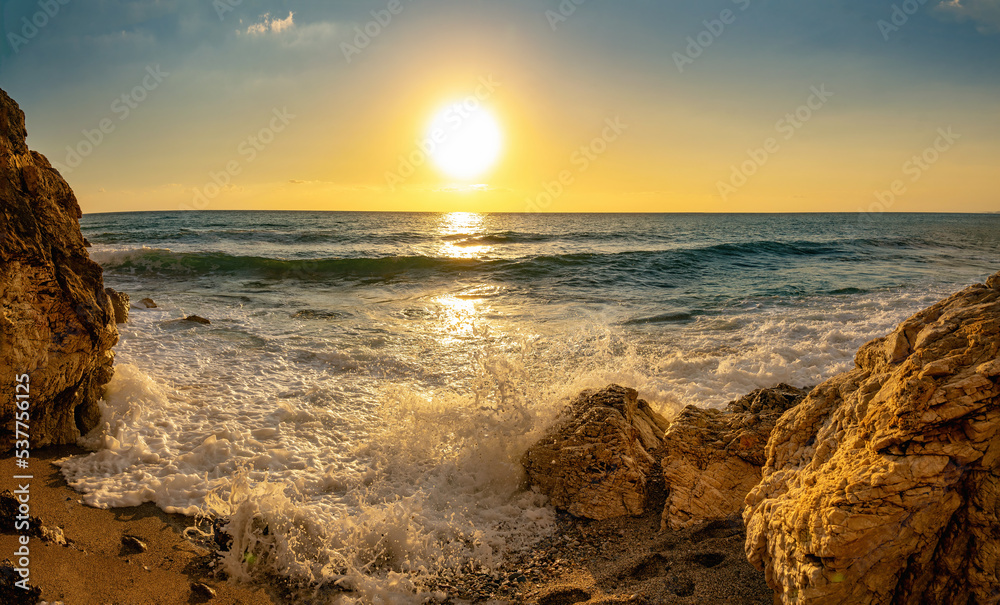 Very beautiful mediterranean seascape with setting sun on sunset. Waves crash on rocks in nature.