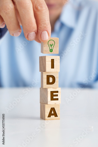 Businesswoman holding wooden block with light bulb on it. Idea concept.