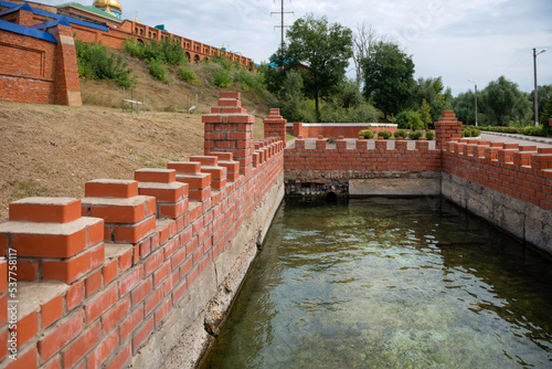 Open pool with spring water at the walls of the Zadonsky Nativity of the Virgin Mary Monastery photo