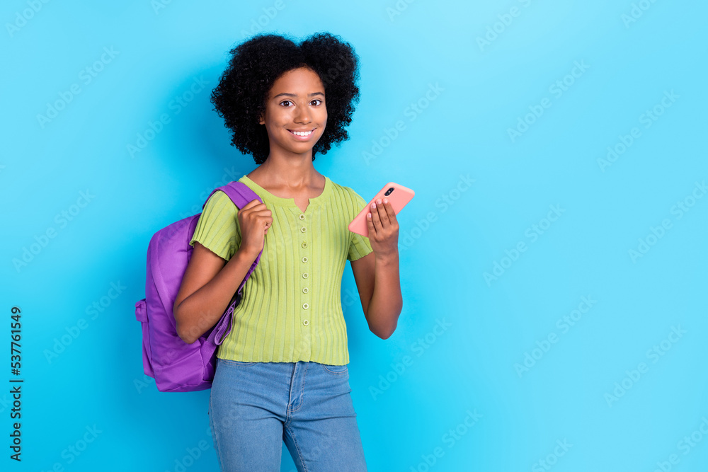 Portrait of positive girl curly hair green t-shirt hold smartphone facebook twitter instagram whatsapp isolated on blue color background