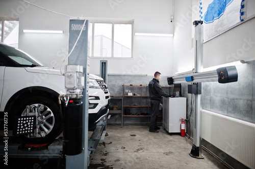 Auto mechanic sets american SUV car for diagnostics and configuration camber check in workshop of service station..