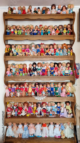 a lot of dolls in different clothes on shelves in a souvenir shop, collection of children toys