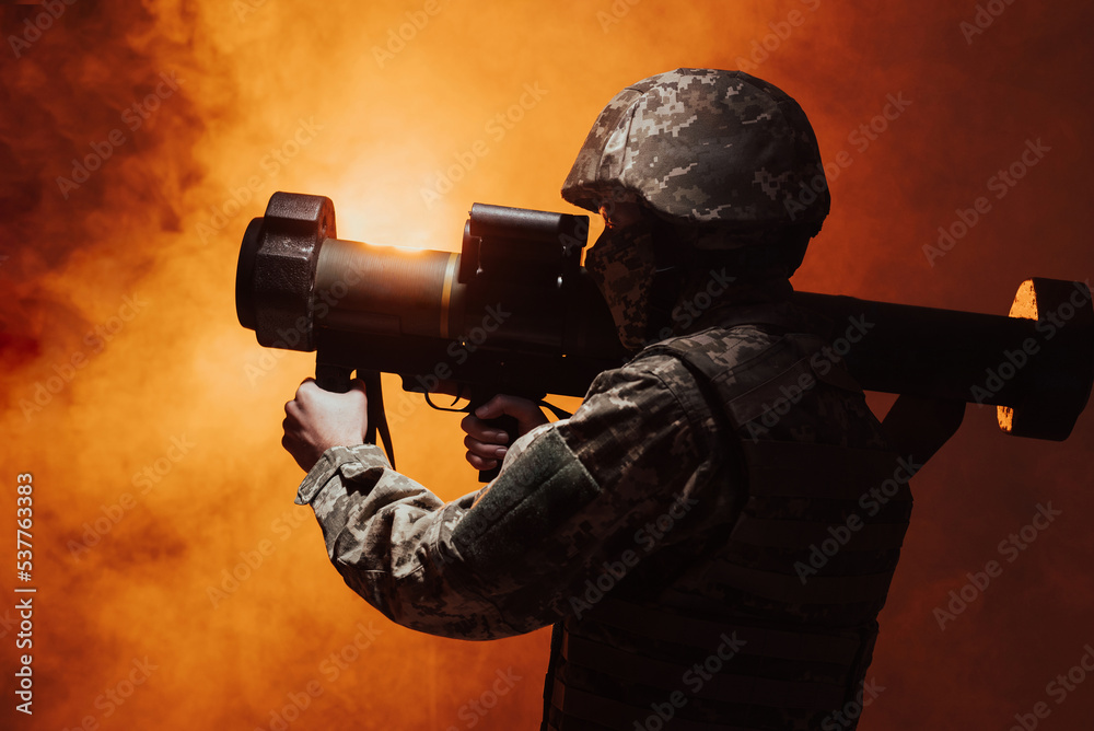 Military missile, combat, combat, war, big gun shooting. Action. Silhouette of a military soldier firing a grenade launcher. studio shot with colour orange  smoke 
