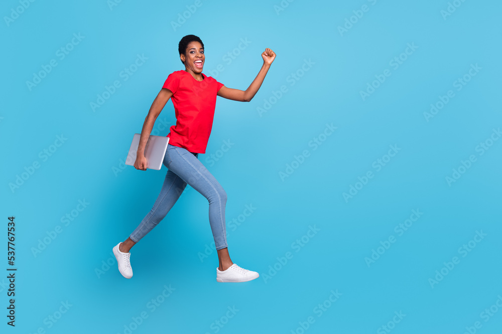Photo of cute charming short hair person dressed red t-shirt hurrying jumping carrying modern gadget isolated blue color background Photo of cute charming short hair person dressed red t-shirt hurrying jumping carrying modern gadget isolated blue color background
