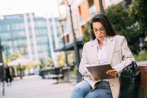 Portrait of a business woman using digital tablet during quick break in front a corporate building.