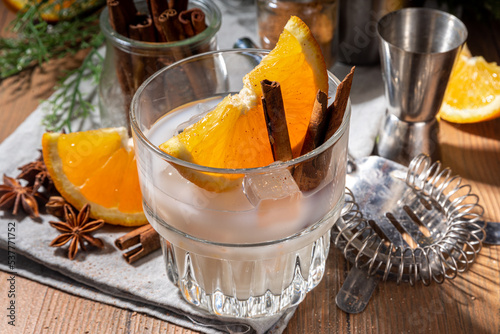 Autumn alcohol drink, boozy refreshing milk and honey cocktail with benedictine orange and cinnamon spice, wooden kitchen table background copy space photo