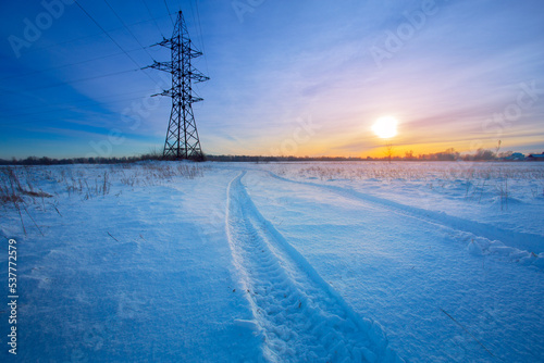 Snow-covered landscape with power poles on a cold winter evening