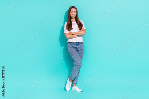 Portrait of adorable pretty cute woman with long hairdo dressed striped t-shirt jeans arms crossed isolated on teal color background