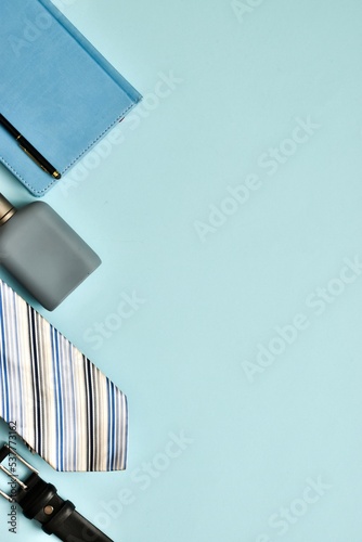 Belt, necktie, cologne and diary on a light blue background. Vertical photo, copy space. Flat lay. Fathers day, Boss day, mens day, valentine's day for holiday banner. Template for Greeting card.