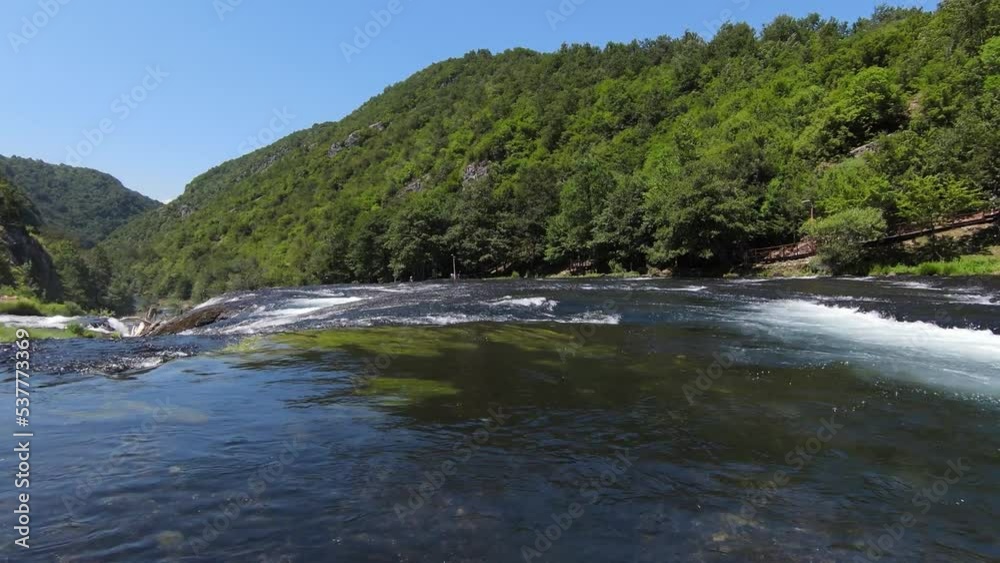 FPV Aerial shot skilled flying at natural landscape river Una with waterfall Strbacki Buk in the dense green forest under trees.