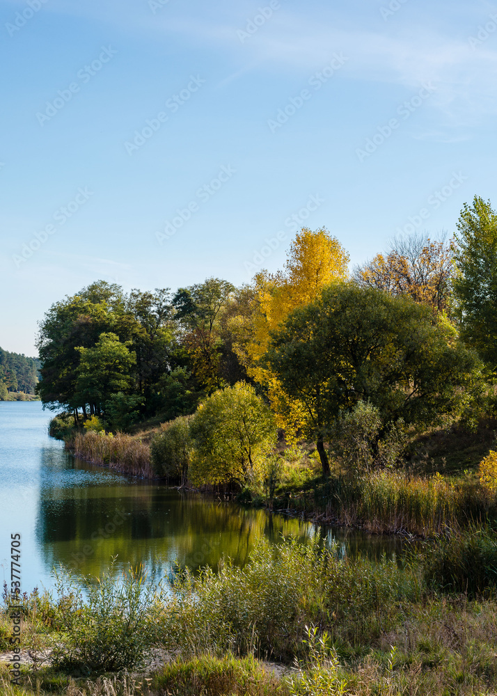 Beautiful autumn landscape. Pine and deciduous forest, clear lake and blue sky. Autumn in Chernigov, Ukraine