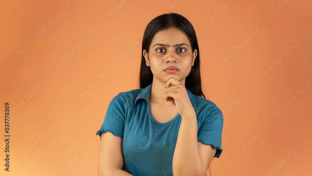 Pretty young woman looking up empty space deep thinking, holding arm on chin, isolated color background