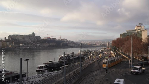 Traffic in Budapest Hungary, tram and cars crossing junction, Buda Castle and Chain Bridge in background, gimbal shot
