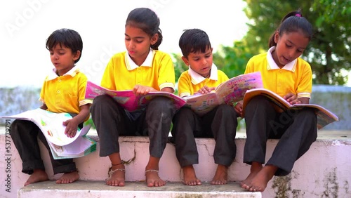 Young Asian Indian students reading books, studying, preparing for exam or working on group project, staircase or steps of school campus
