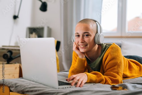Εκτύπωση καμβά teenager shaved head female with headphones laying on bed in her room and using