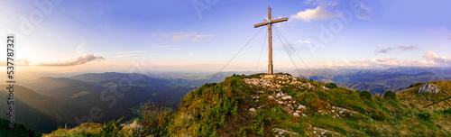 Tableau sur toile Panorama of summit cross and sunset over the mountains on peak Kirchstein in the