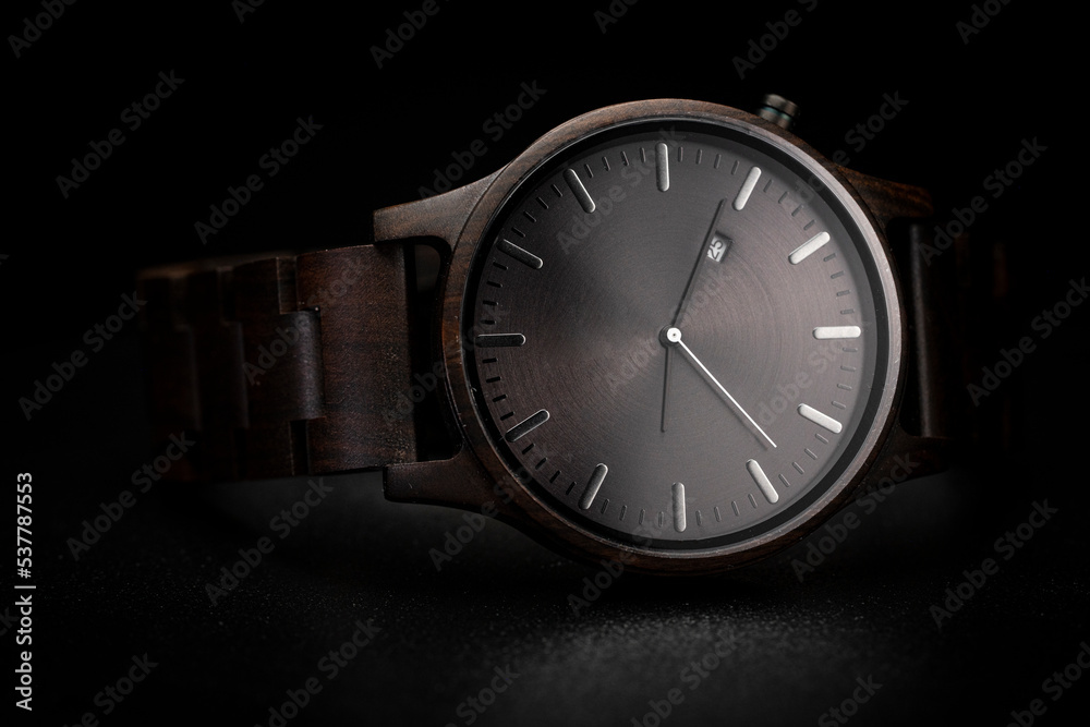 Dark brown wooden watch on a clean black background Dark brown wooden watch on a clean black background