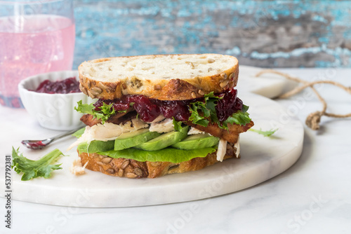 A delicious turkey and bacon club sandwich with avocado and cranberry sauce.