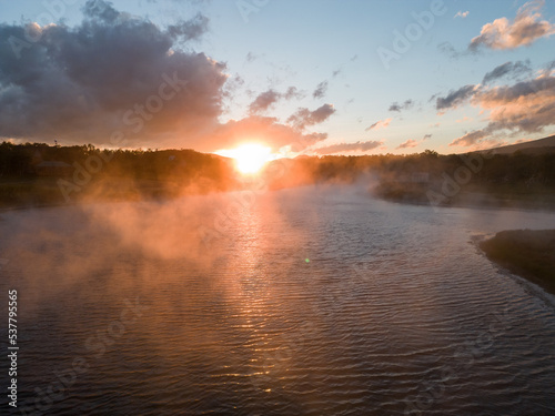 Spectacular dawn (positive mood), time of fog birth. Fog creeps over river on rising sun background.