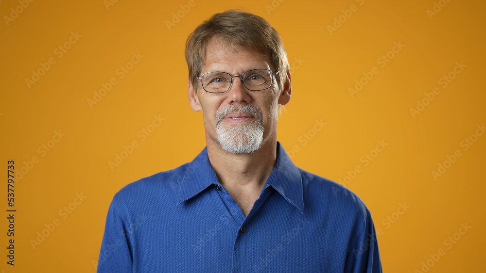 Smiling cheerful happy mature bearded man in blue shirt isolated on solid yellow background studio. People sincere emotions lifestyle concept. Smiling cheerful happy mature bearded man in blue shirt isolated on solid yellow background studio. People sincere emotions lifestyle concept.