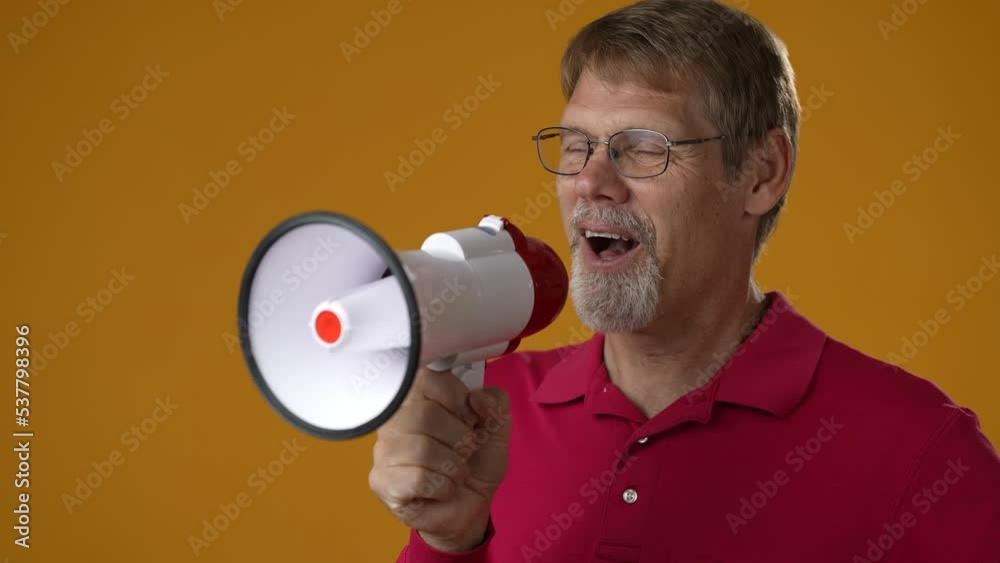 Fun elderly bearded man 50s wears red shirt yells into megaphone announces discounts sale Hurry up isolated on solid yellow background studio portrait Fun elderly bearded man 50s wears red shirt yells into megaphone announces discounts sale Hurry up isolated on solid yellow background studio portrait