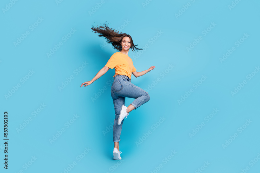 Full length photo of pretty sweet girl dressed yellow t-shirt dancing isolated blue color background Full length photo of pretty sweet girl dressed yellow t-shirt dancing isolated blue color background