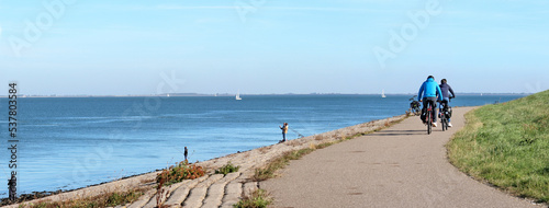 Fishing people and bikers on the sea defence dike along the Eastern Scheldt estuary in Zeeland province, the Netherlands photo