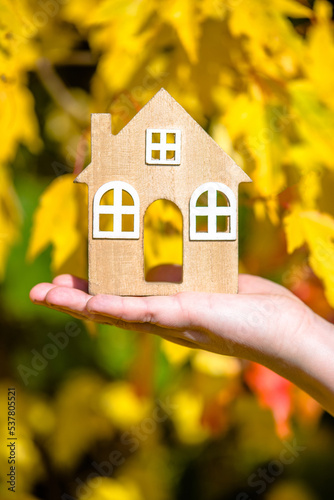 The symbol of the house in the girl's hand on the background of yellow leaves