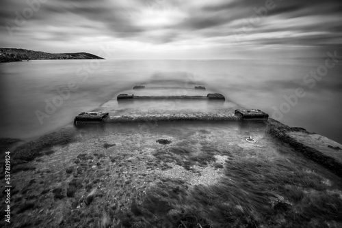 old pier in water with clouds on sky black and white © Aytug Bayer