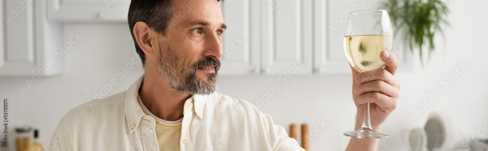 bearded man in white shirt looking at glass of white wine in kitchen, banner bearded man in white shirt looking at glass of white wine in kitchen, banner