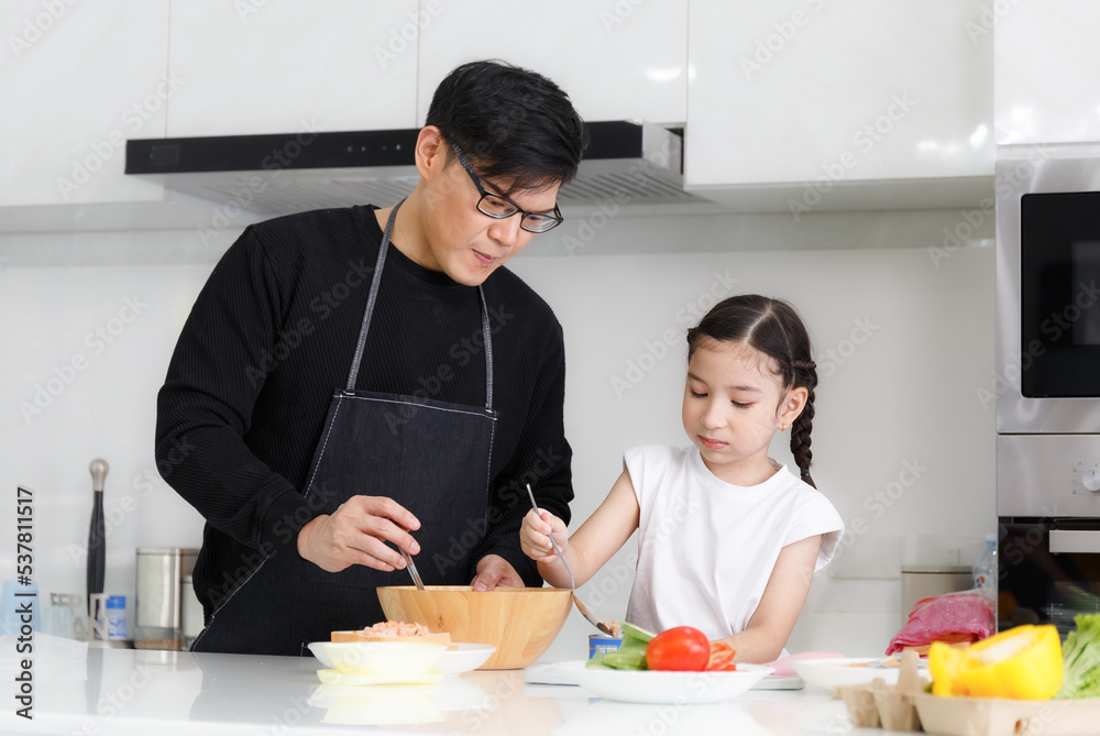 A happy family cooks together in the kitchen. The adorable fathe