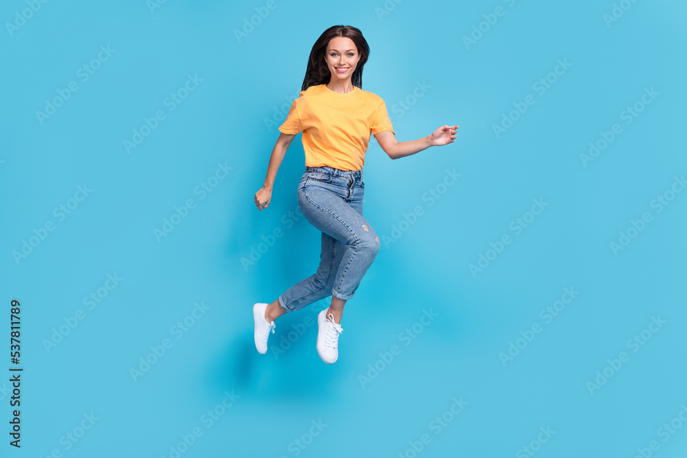 Full length photo of pretty excited lady wear yellow t-shirt jumping high running fast isolated blue color background