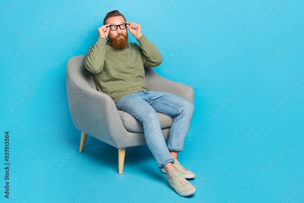 Full size photo of intelligent man with red hairstyle wear khaki pullover touch glasses look empty space isolated on blue color background