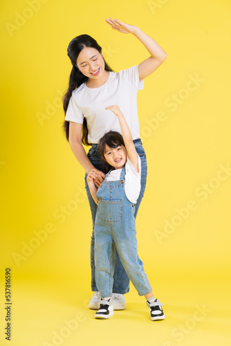 image of asian mother and daughter posing on a yellow background