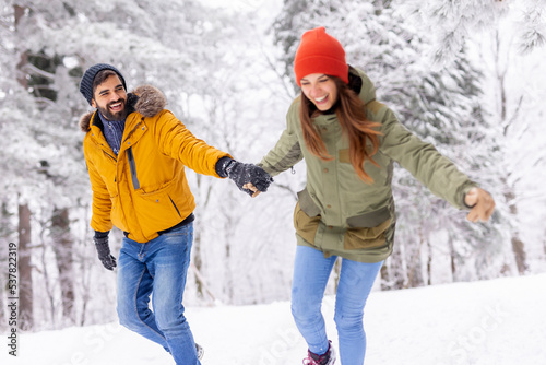 Couple having fun running in the snow while on winter vacation