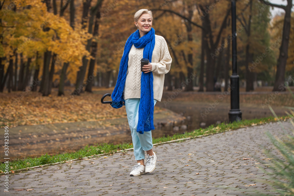 Beautiful middle-aged woman walking in autumn park Beautiful middle-aged woman walking in autumn park