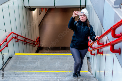 Young woman takes a photo as she exits the metro station. photo