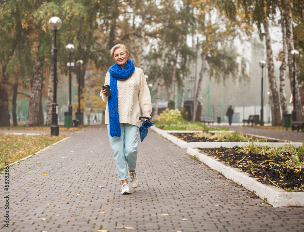 Obraz premium Beautiful middle-aged woman walking in autumn park