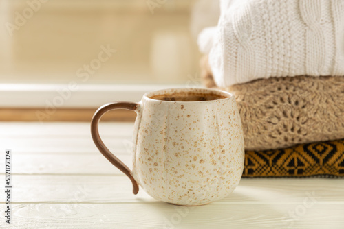 Autumn. Autumn composition, a hot cup of coffee and a warm sweater on a wooden textured table. Seasonal, morning hot coffee.Relaxing and still life concept. Cozy interior