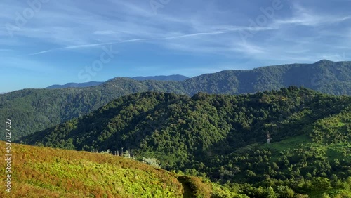 Mountains aesthetic panorama view from above. Peak of Gonio mountain in Adjara, Georgia. Blue sky with clouds, green valley and red woods