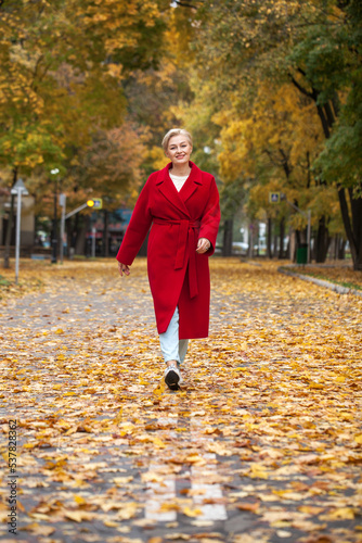 Portrait of a beautiful middle-aged woman in a red coat, autumn park